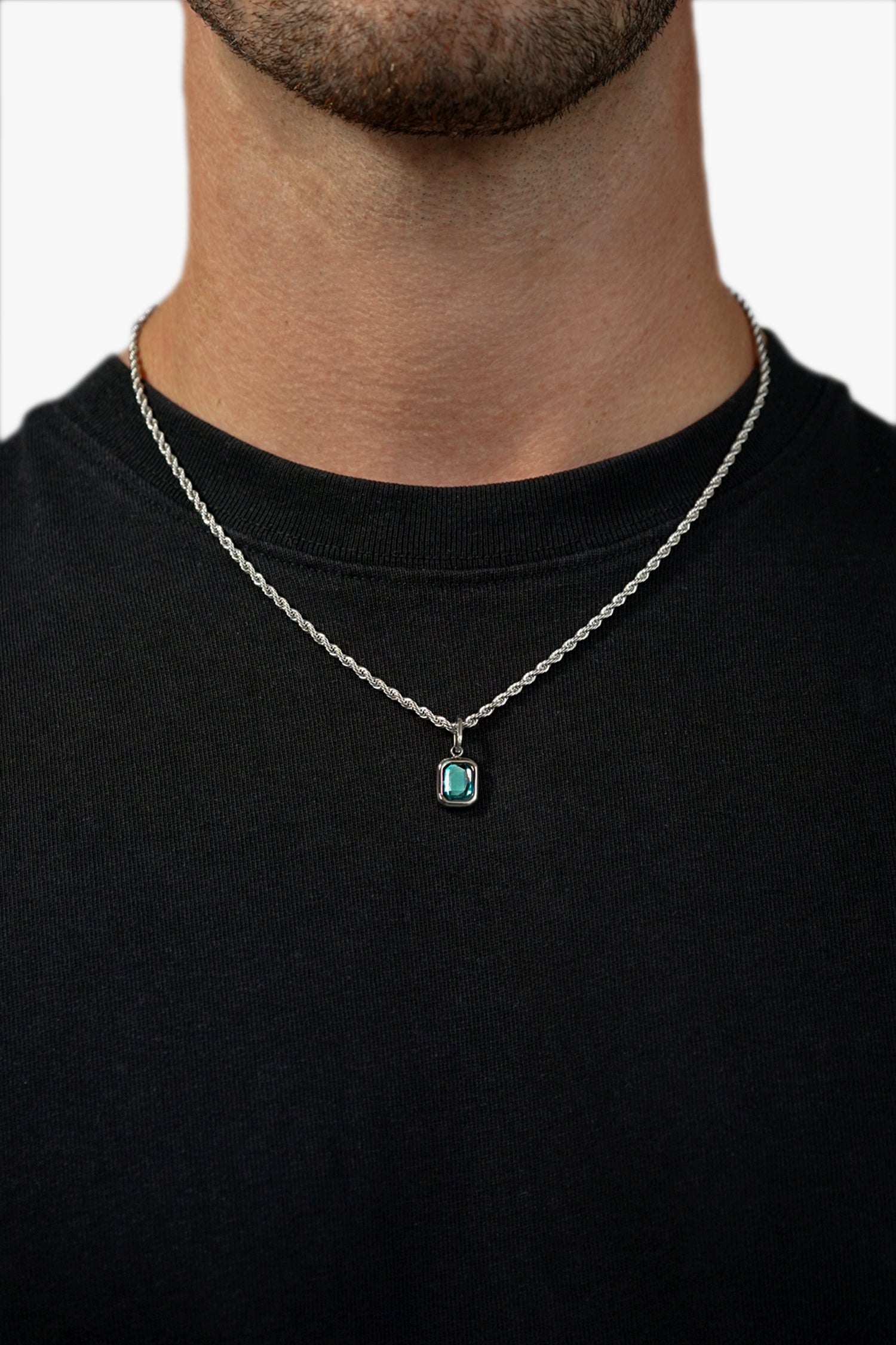 FRNE glacier blue gemstone silver pendant necklace worn by a person, featuring a rectangular light blue stone on a silver chain styled against a black t-shirt for contrast