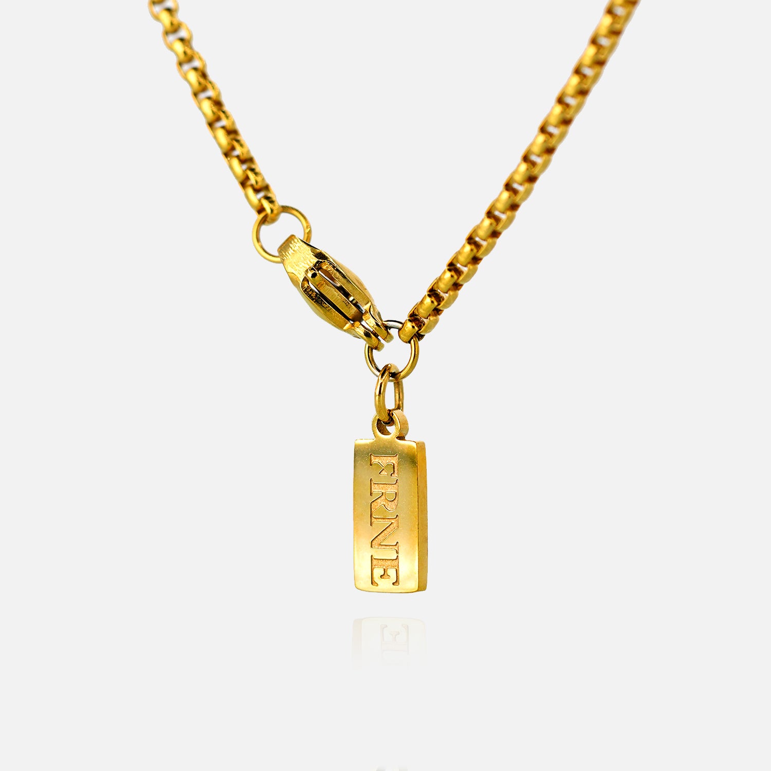 Gold necklace with a rectangular tag pendant engraved with “FRNE” on a white background with a subtle reflection