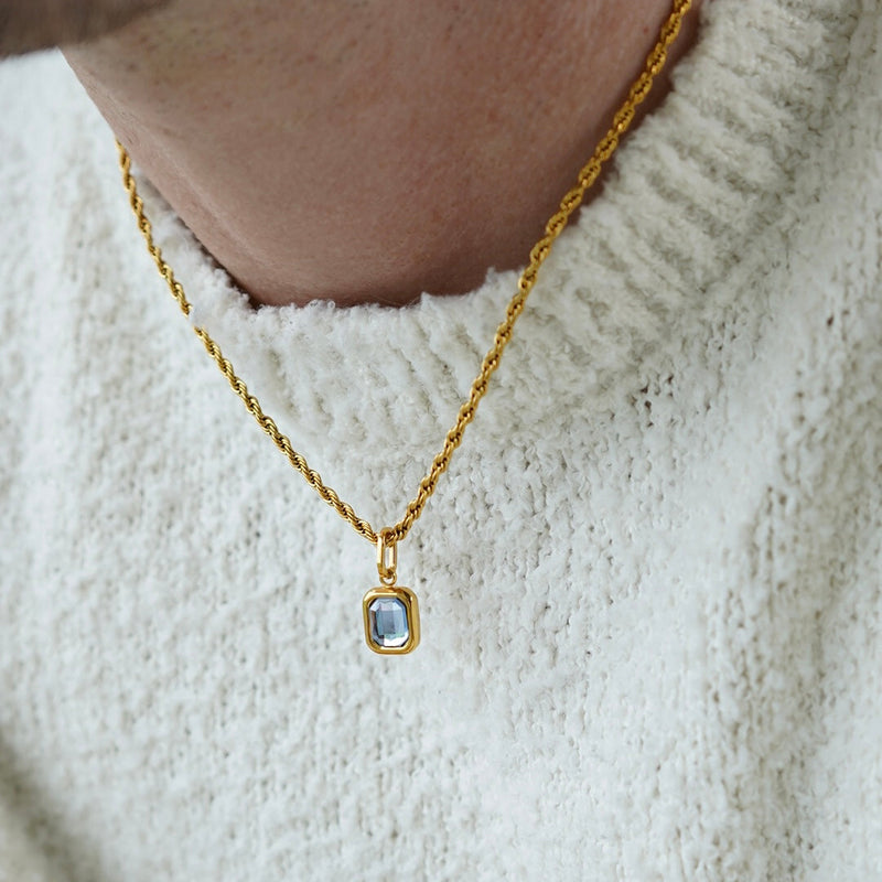 FRNE gold tanzanite pendant necklace with blue gemstone worn on neck with white sweater close up