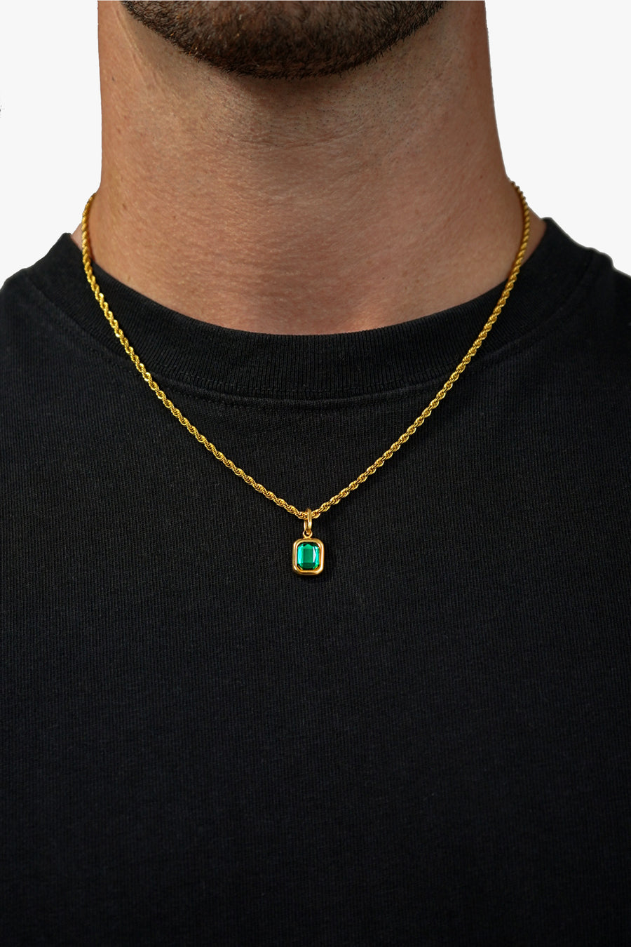FRNE lucky gem green gemstone gold necklace worn by a person, featuring a rectangular emerald-green pendant on a gold chain, styled against a black shirt for strong contrast