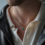 FRNE lucky gem green gemstone gold necklace worn by a person, featuring a rectangular emerald-green pendant on a gold chain, styled with a white shirt and black leather jacket in a close-up portrait