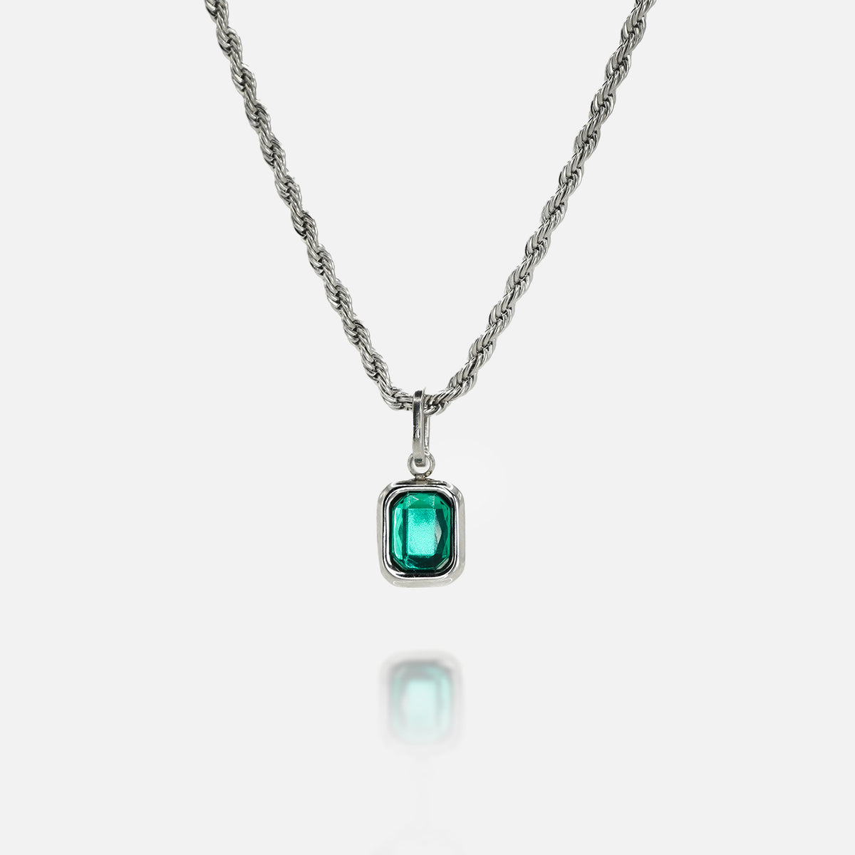 Silver necklace with a rectangular green gemstone pendant on a clean white background, featuring a reflective surface below the pendant