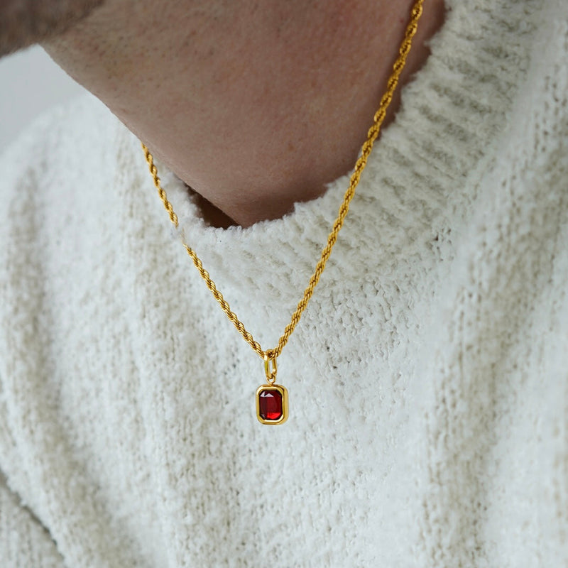 FRNE ruby centre red gemstone gold necklace worn by a person, featuring a small rectangular deep red stone pendant set in gold on a rope-style chain, styled on a white textured sweater