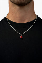 FRNE ruby flame red gemstone silver necklace worn by a person, featuring a small rectangular deep red stone pendant set in silver on a rope-style chain, styled against a black shirt for contrast