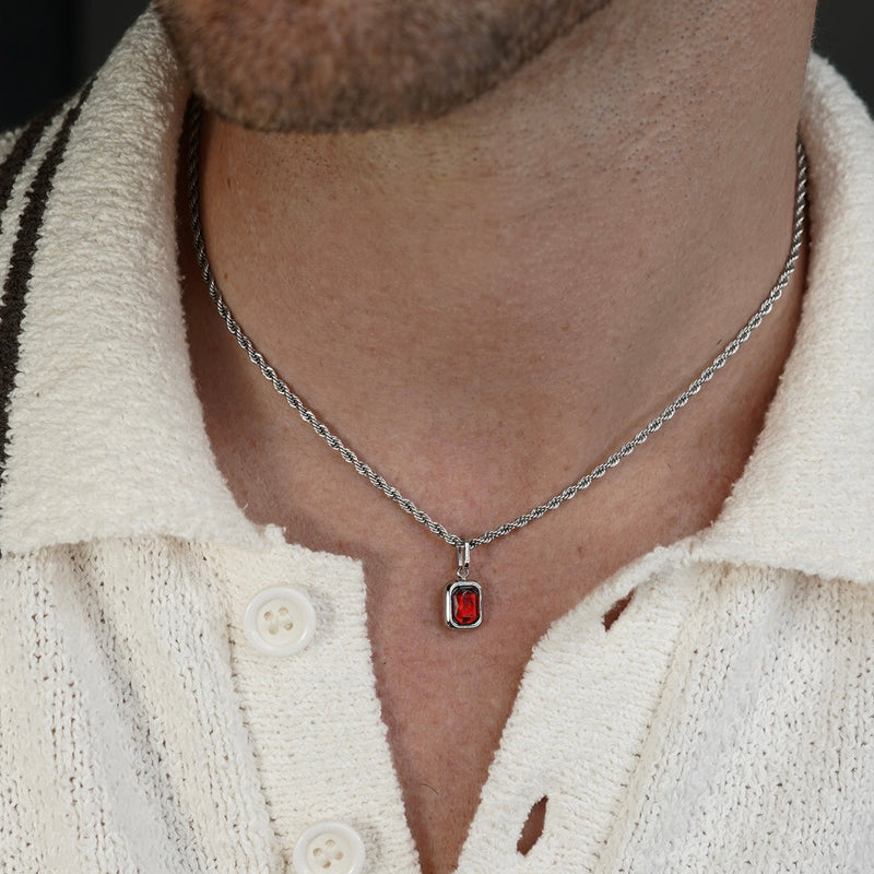 FRNE ruby flame red gemstone silver necklace worn by a person, featuring a small rectangular deep red stone pendant set in silver on a rope-style silver chain, styled on a light textured shirt