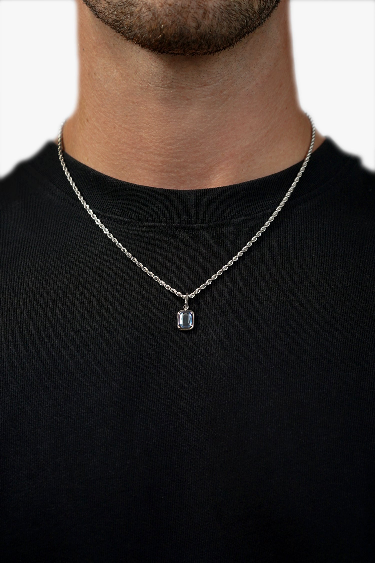 Men’s sterling silver tanzanite pendant necklace with blue gemstone worn with black shirt close up
