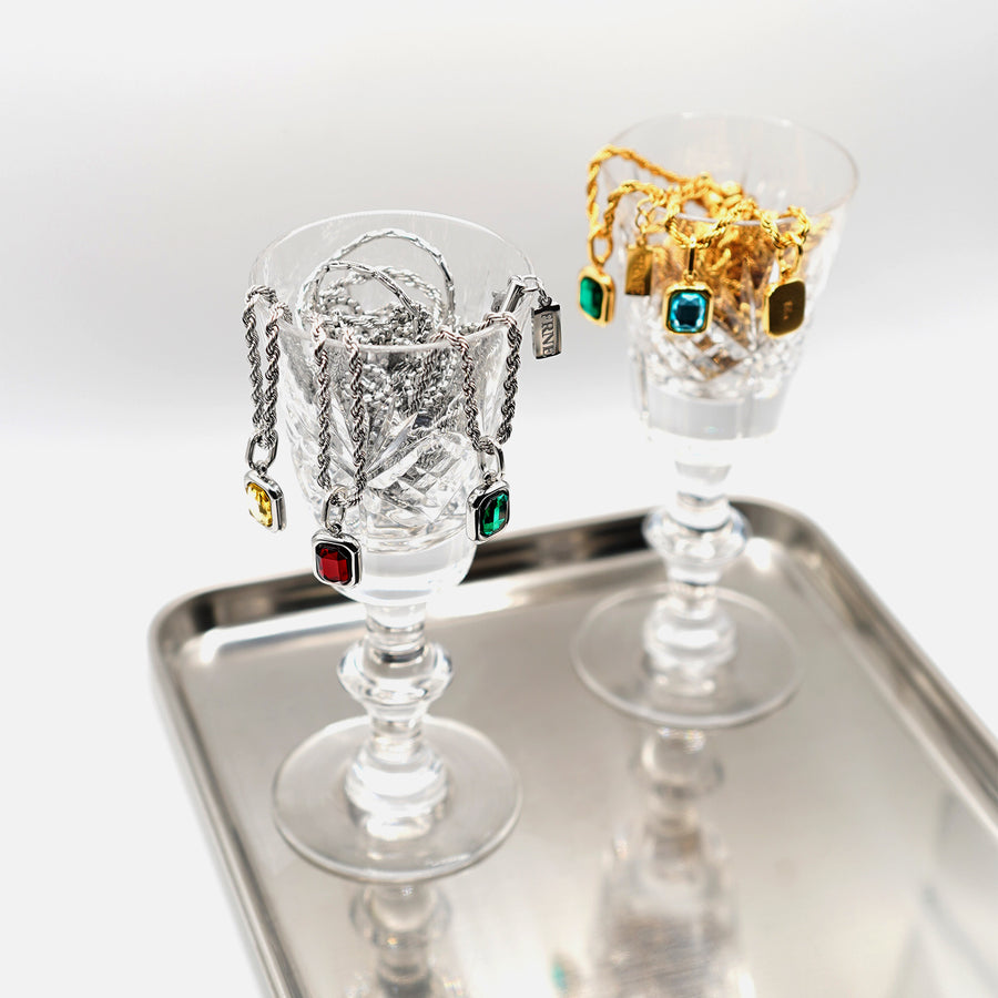 Sterling silver and gold gemstone pendant necklaces displayed in glass cups with colorful rectangular stones