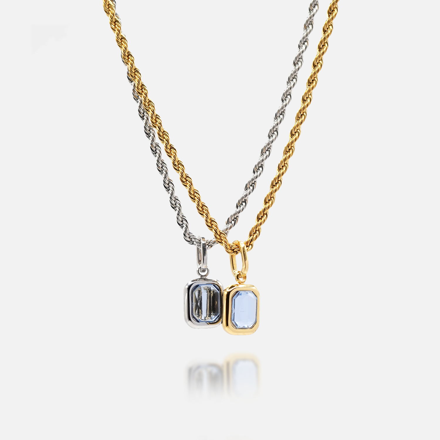 Gold and sterling silver tanzanite pendant necklaces with rectangular blue gemstone on white background