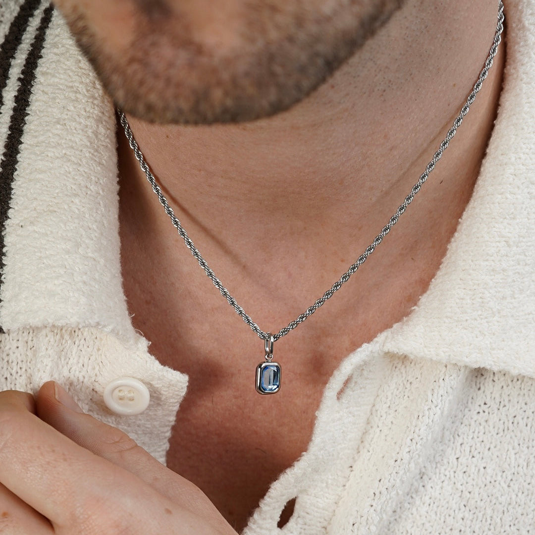 Men’s sterling silver tanzanite pendant necklace with rectangular blue gemstone worn on neck close up